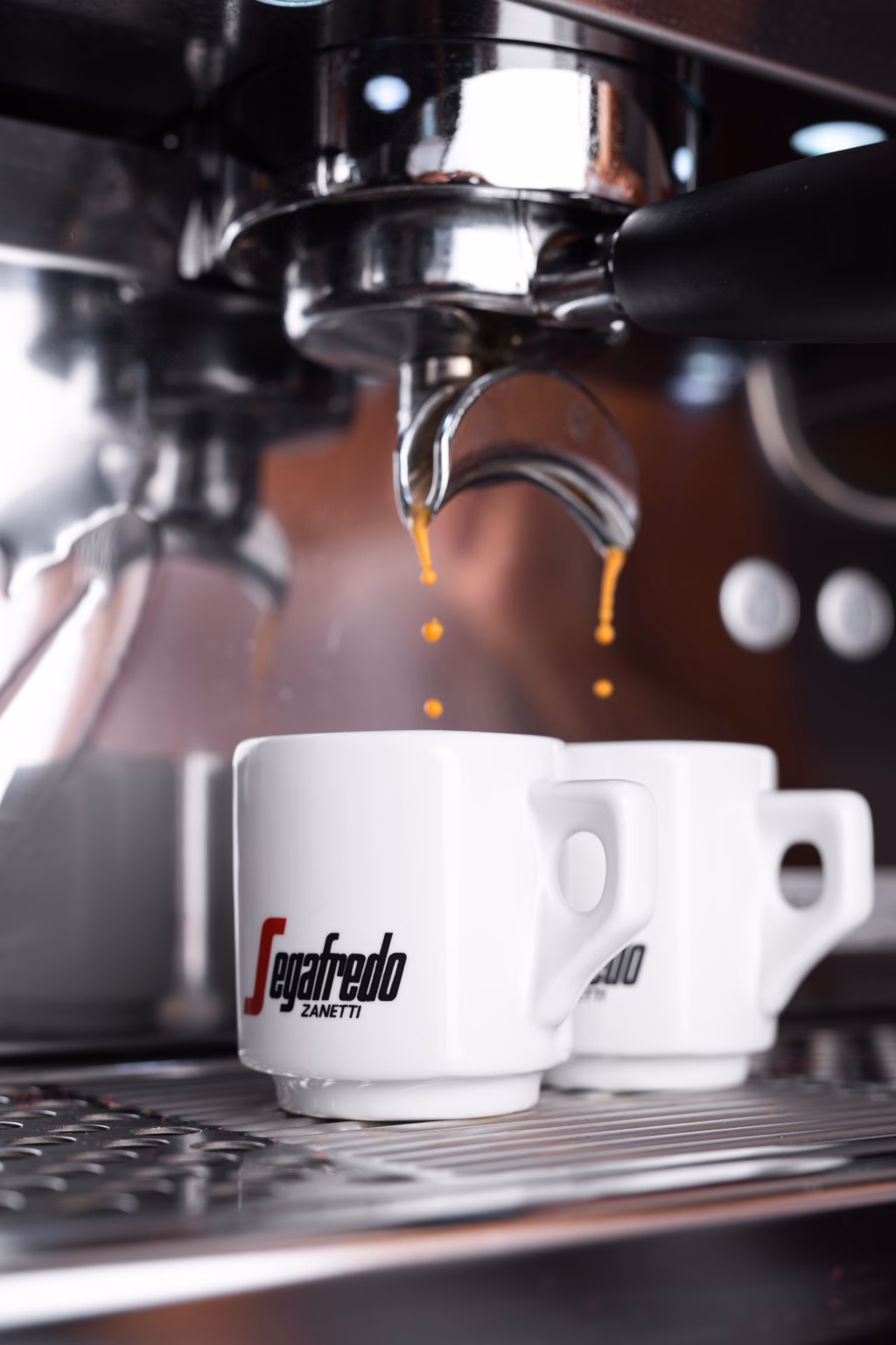 Kaffee fließt aus einem Siebträger in zwei Espressotassen